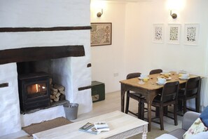 Ein gemütliches Zimmer mit Kamin, einem für das Frühstück gedeckten Esstisch und gerahmten Bildern an der Wand.