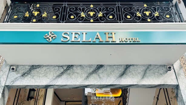 Ein Hotel Eingang mit einem Schild mit der Aufschrift 'SELAH HOTEL' und einem dekorativen Metallgeländer darüber.