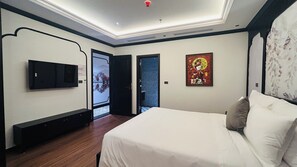 A bedroom with a bed, a TV, a door leading to a bathroom, and a poster on the wall. - Selah Hanoi Hotel (Hanoi)
