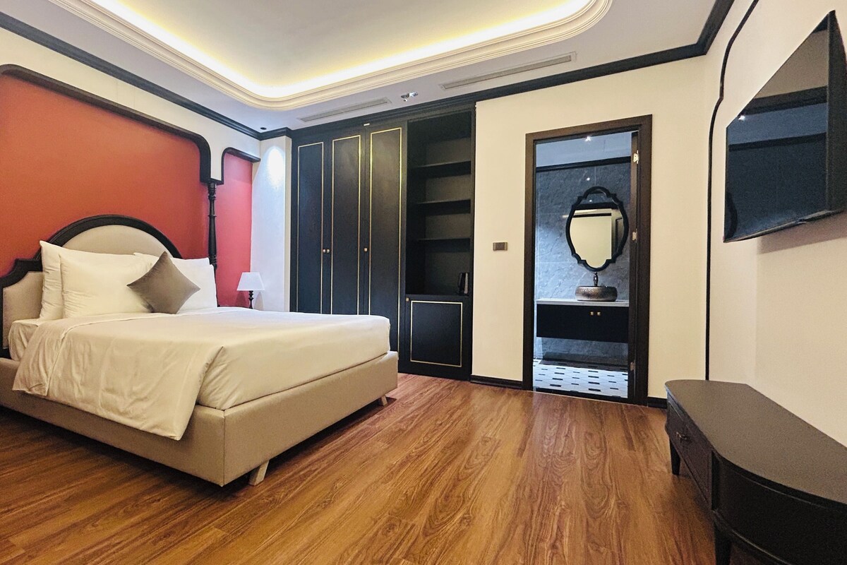 A bedroom with a bed, a wardrobe, a mirror, and a television.