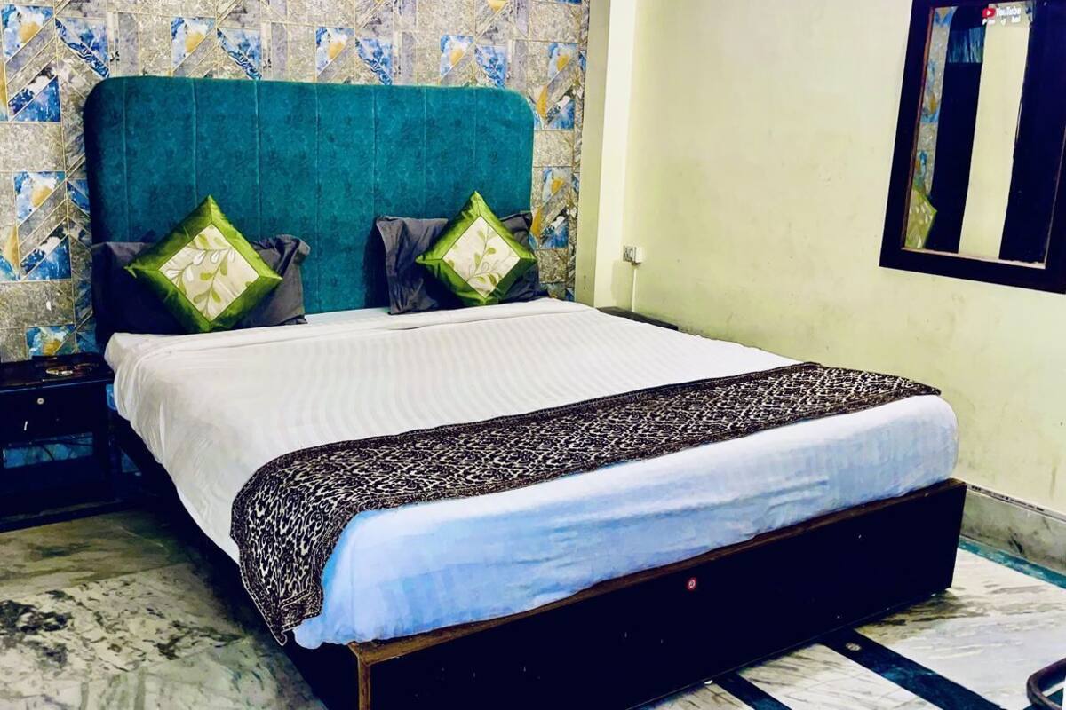 A bed with a patterned bedspread, two pillows, a nightstand, and a tiled wall with a geometric pattern.