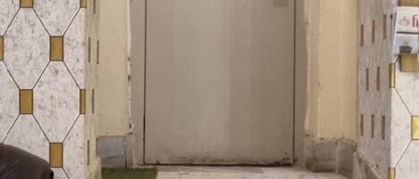 Un conjunto de escalones de mármol que conducen a una puerta con un ventanal y un interruptor de luz.