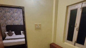 Une pièce comprenant un lit, un canapé, une petite table, une fenêtre et un interrupteur sur le mur.