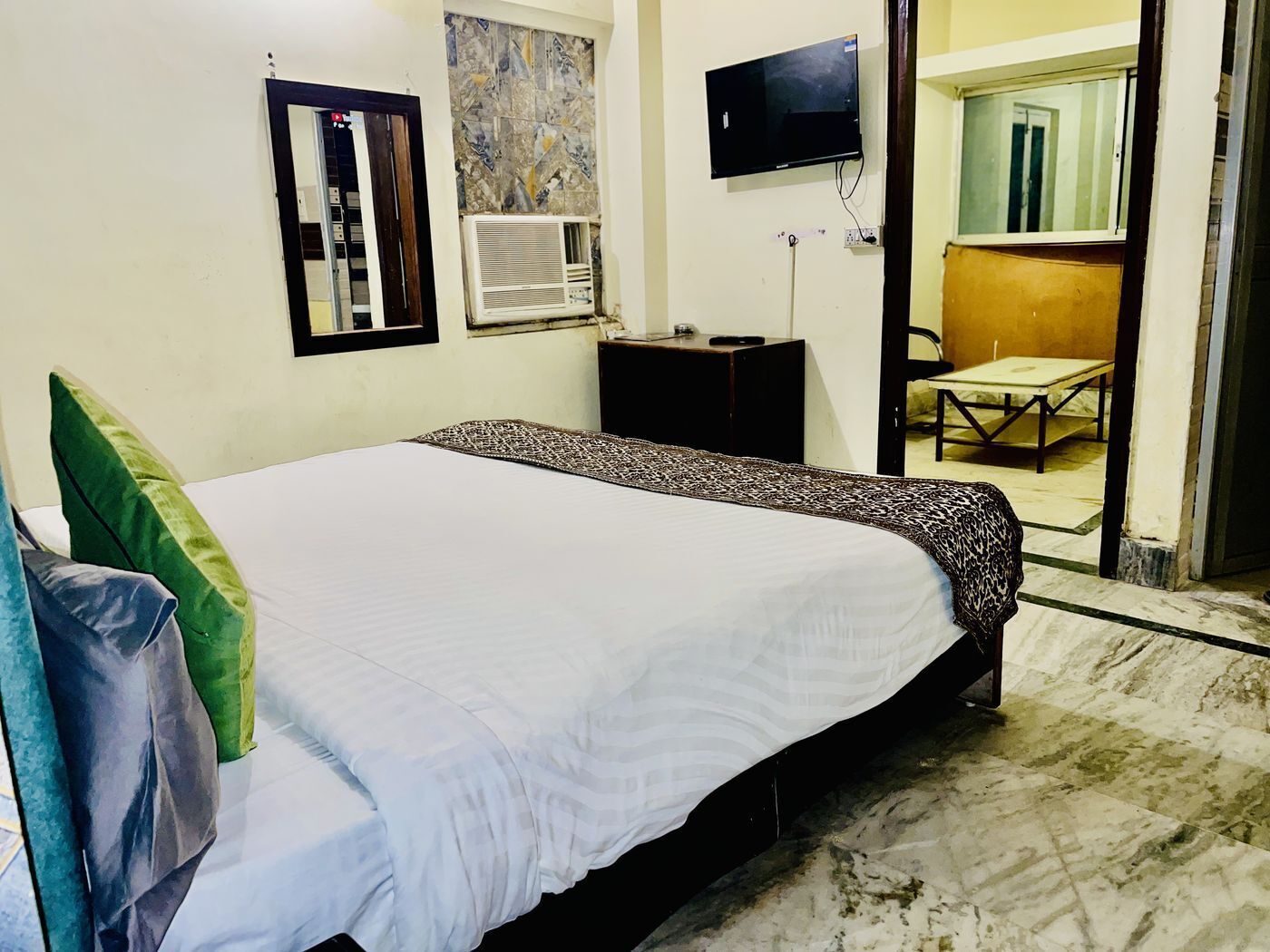 Una habitació d'hotel amb un llit, televisió, aire condicionat, escriptori i cadira.