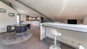 A modern kitchen with a bar area, dining table, and chairs.