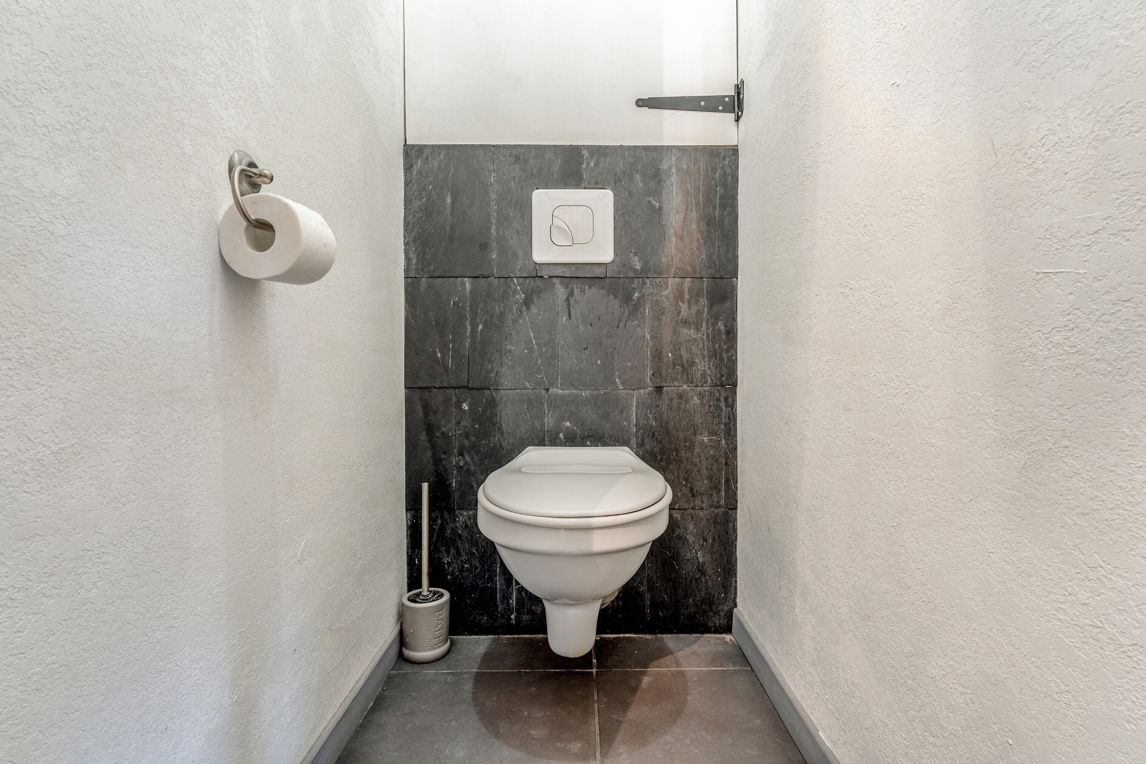 Un baño pequeño con inodoro, dispensador de papel higiénico y bidé.