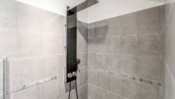 Une douche équipée d’un pommeau de douche à main et d’un panneau de commande fixé au mur.