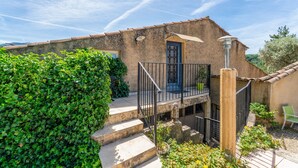 A rustic building with a stone facade, a balcony with a metal railing, and a door with a decorative glass panel.