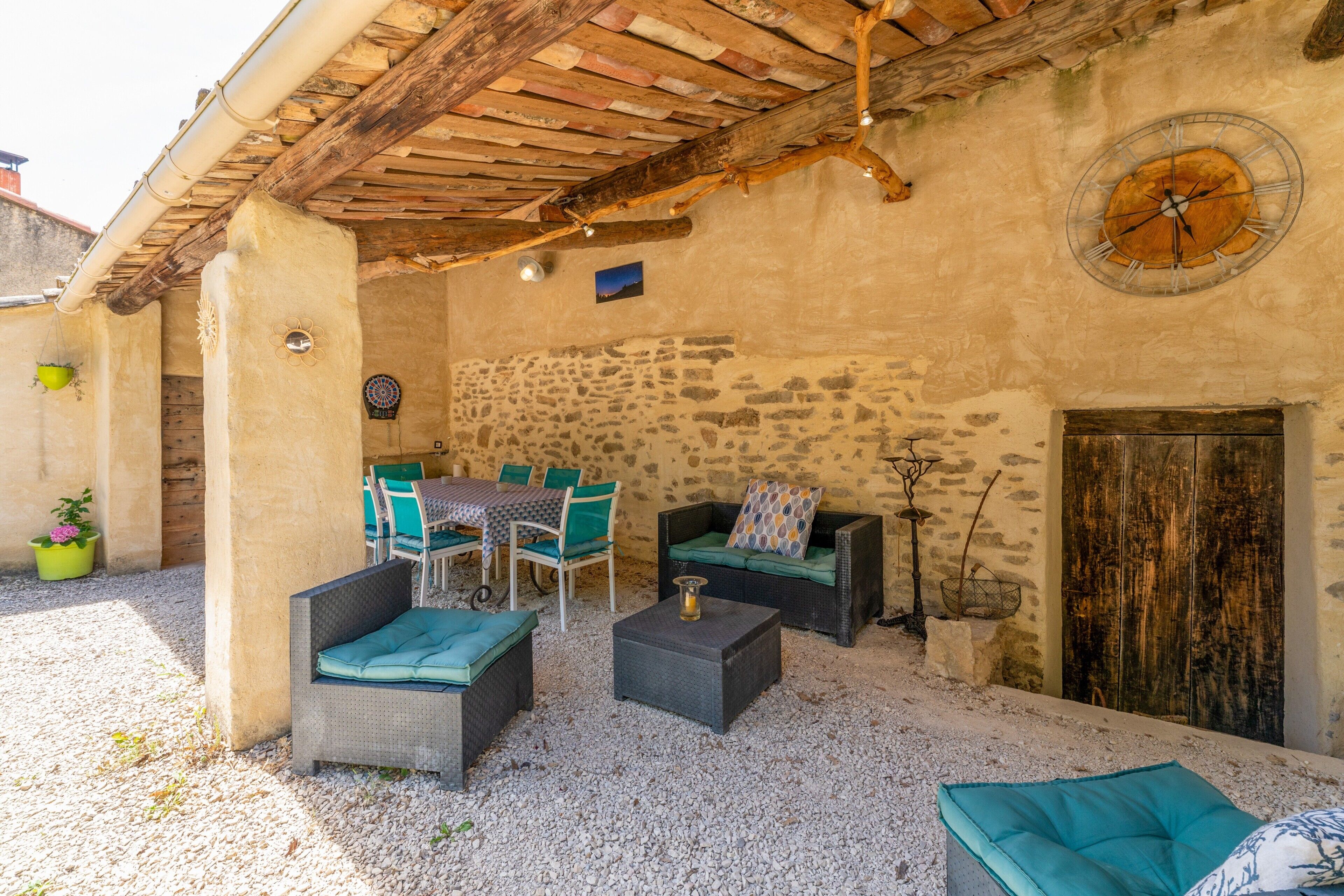 Eine Terrasse im Freien mit Korbmöbeln, einer Steinmauer und einer rustikalen Holzdecke.