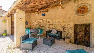 Eine Terrasse im Freien mit Korbmöbeln, einer Steinmauer und einer rustikalen Holzdecke.