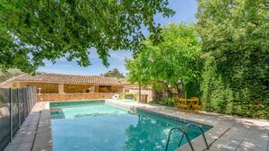 A swimming pool with a stone building in the background, surrounded by trees.