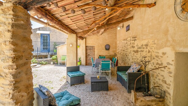 An outdoor patio with wicker furniture, a table, and a rustic stone wall.