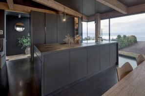 Una cucina moderna con una grande isola, mobili scuri e vista mare.