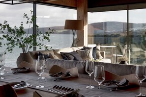 Zona pranzo con vista mare, un divano e un tavolo apparecchiato per un pasto.