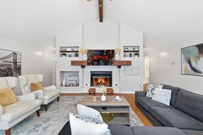 Ein Wohnzimmer mit Kamin, Netflix-Logo, einer Couch, einem Couchtisch und einem Bücherregal.