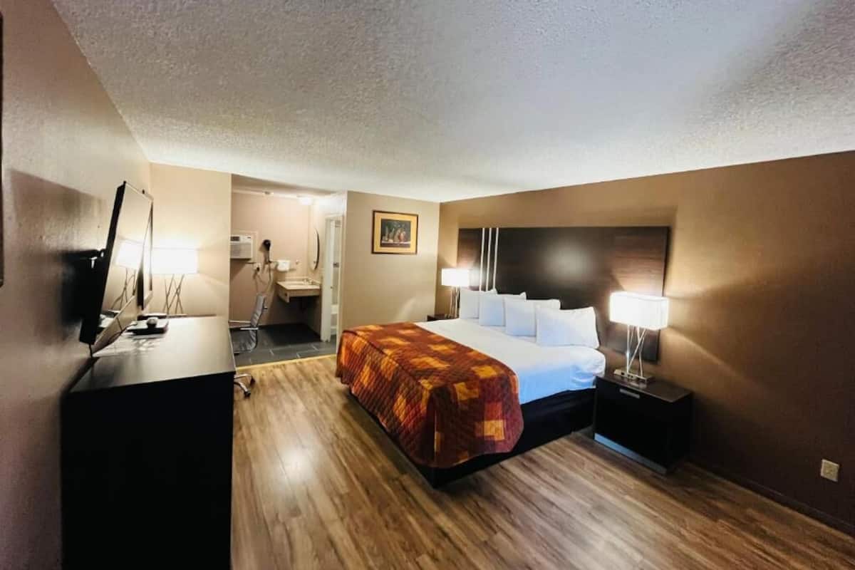 A hotel room with a bed, bedside lamps, a desk, and a chair.