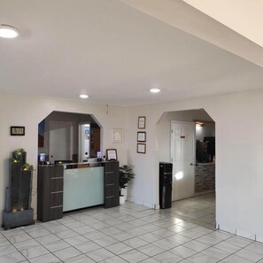 A reception area with a reception desk, framed pictures on the wall, and a tiled floor. - Star Inn (Tonopah)
