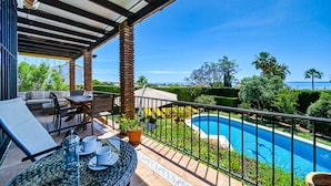 A covered outdoor area with a pool, seating, and potted plants. - W12 Andalusian style villa with sea views (Mijas Costa)