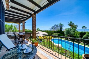 A covered outdoor area with a pool, seating, and potted plants. - W12 Andalusian style villa with sea views (Mijas Costa)