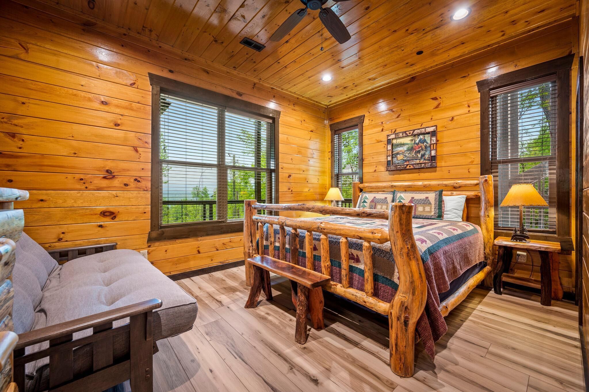 Ein Schlafzimmer in einer Blockhütte mit einem Holzbett, einem Sofa und einem Deckenventilator.