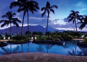 A pool with palm trees and a mountain view.