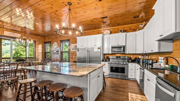 A spacious kitchen with a large island, white cabinets, stainless steel appliances, and a wooden ceiling. - The Great Maple Retreat (Gatlinburg)