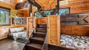 A cabin with a wooden interior, a staircase, and a bed with a quilt. - The Great Maple Retreat (Gatlinburg)