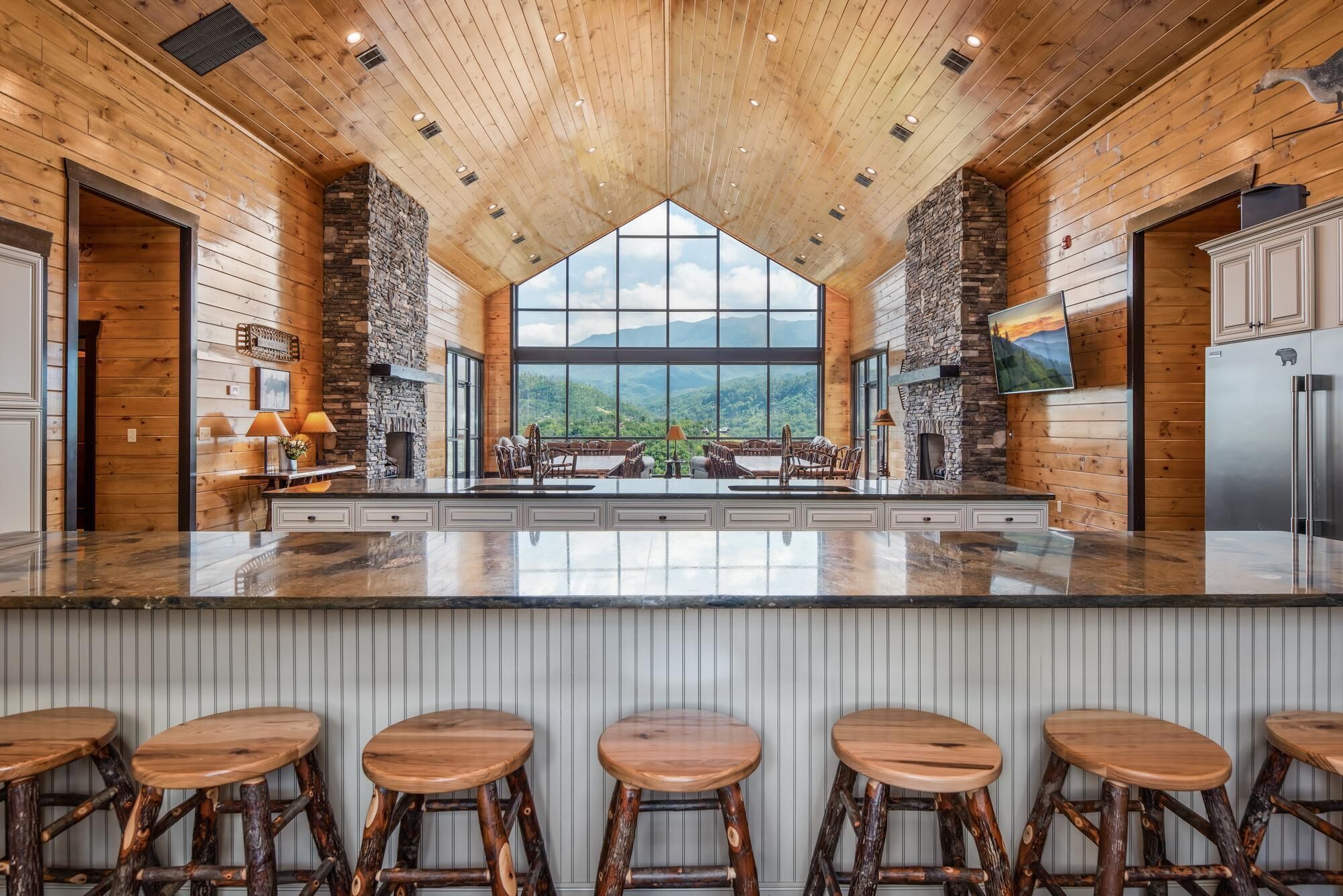 A spacious kitchen with a large island, stone fireplace, and a view of the mountains.