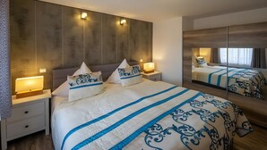 A hotel room with a large bed, bedside lamps, a nightstand, and a mirror reflecting the bed and window. - Apartment "Seeidyll" for 2–4 Guests (48 m²) in Schalkenmehren by the Lake (Schalkenmehren)