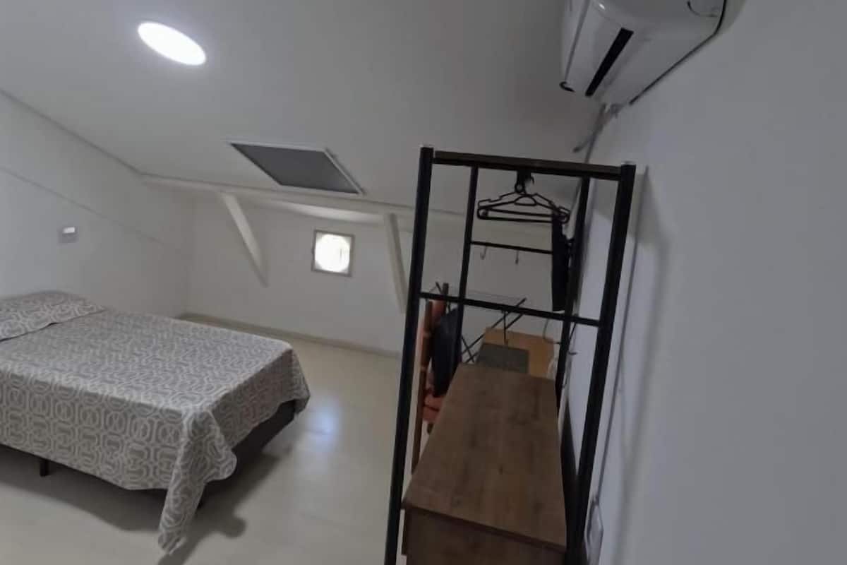 A bedroom with a bed, a heater, and a window.