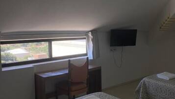 Ein Zimmer mit zwei Betten, einem Schreibtisch, einem Stuhl, einem Fernseher und einem Fenster mit Blick.