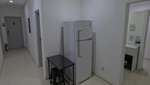 A modern kitchen with a refrigerator, a small table, and a chair. - HAUSHostel (Vinhedo)