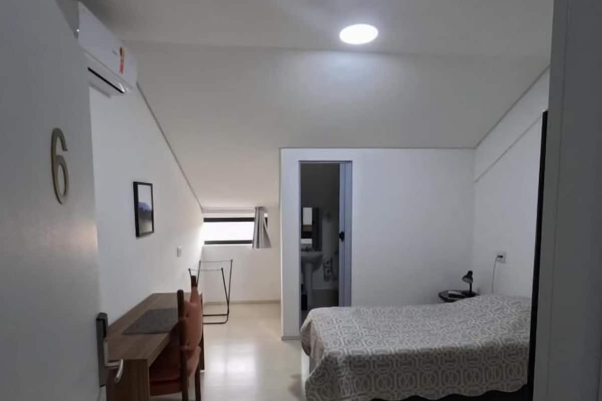 A bedroom with a bed, a desk, and a chair.