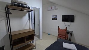 A room with bunk beds, a desk, a chair, a TV, and an air conditioner. - HAUSHostel (Vinhedo)