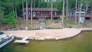 Uma cabana à beira do lago com um píer, um deck e um barco pequeno.