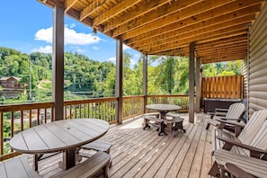 Eine Holzterrasse mit Tisch und Stühlen, mit Blick auf ein bewaldetes Gebiet.