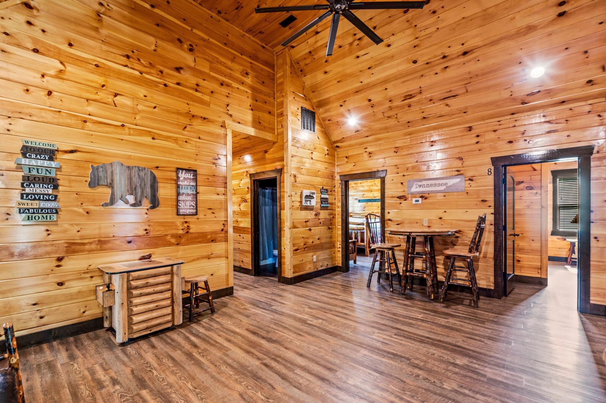 A wooden cabin interior with a dining area, a sign reading 'Welcome,' and a 'Tennessee' sign.