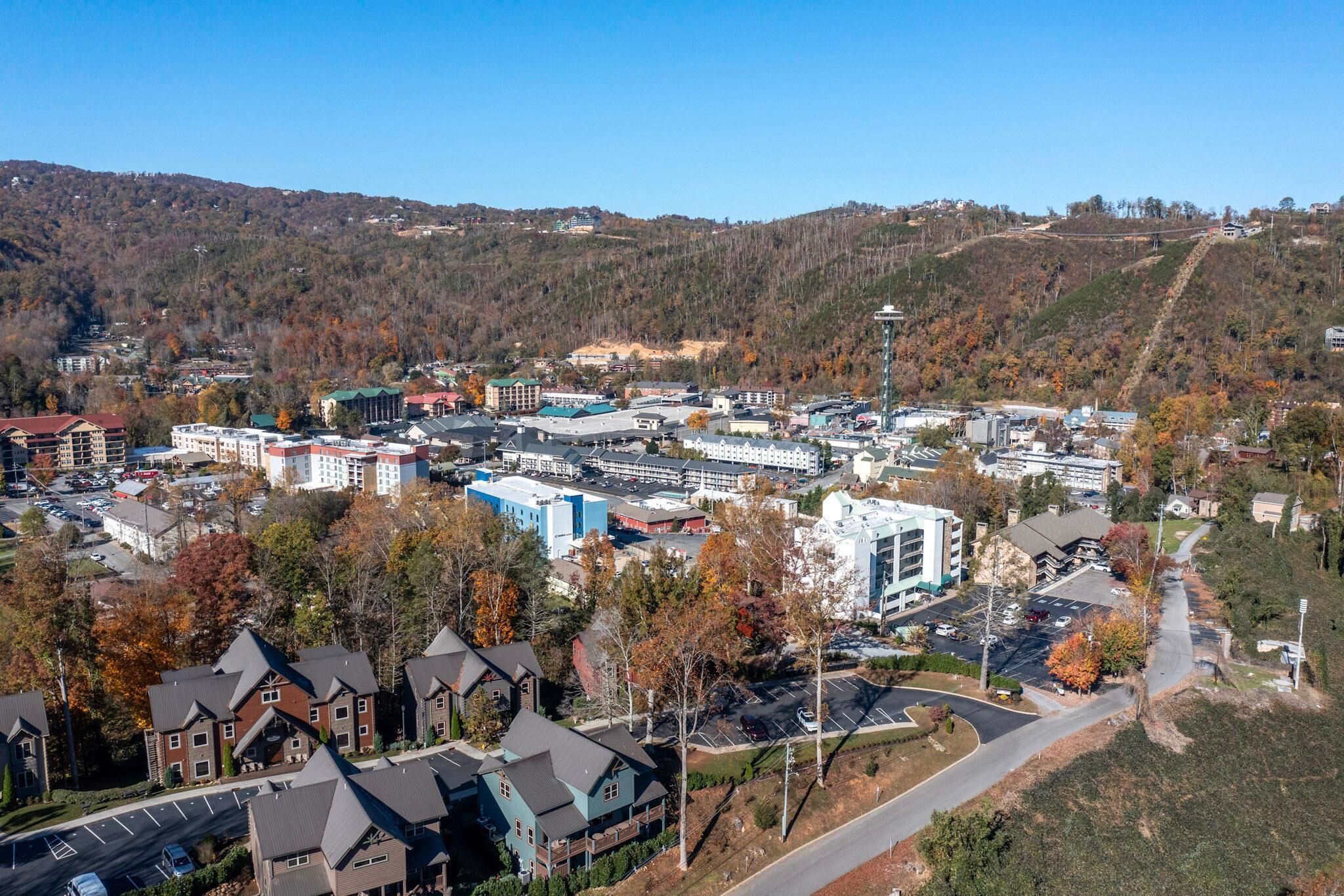 Une ville où se côtoient des immeubles résidentiels et des bâtiments commerciaux, dominée par une tour imposante et bordée de collines.