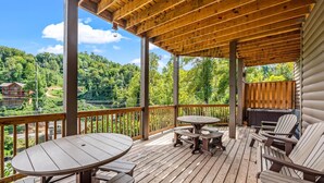 A wooden deck with a table and chairs, overlooking a forested area. - The Majestic Pine Retreat (Gatlinburg)