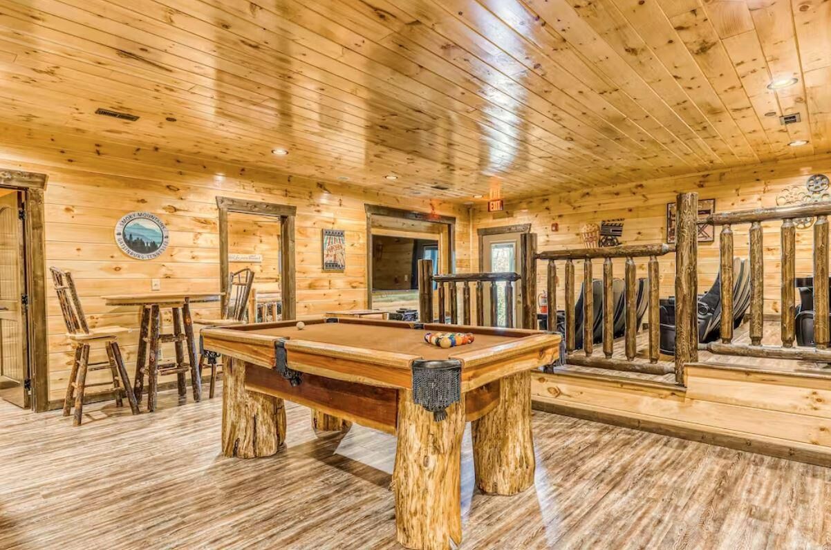 Un intérieur en bois avec une table de billard, des chaises et une rambarde en bois.