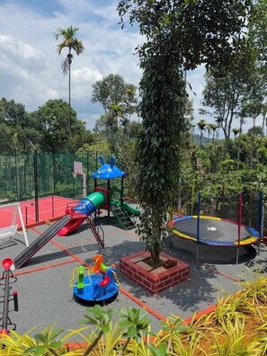 Une aire de jeux avec un toboggan, des balançoires et une structure d’escalade.