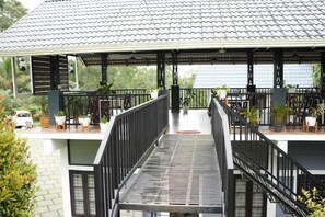 Un espace extérieur abrité, doté d’un escalier en métal, de plantes en pot et d’un bâtiment blanc en arrière-plan.