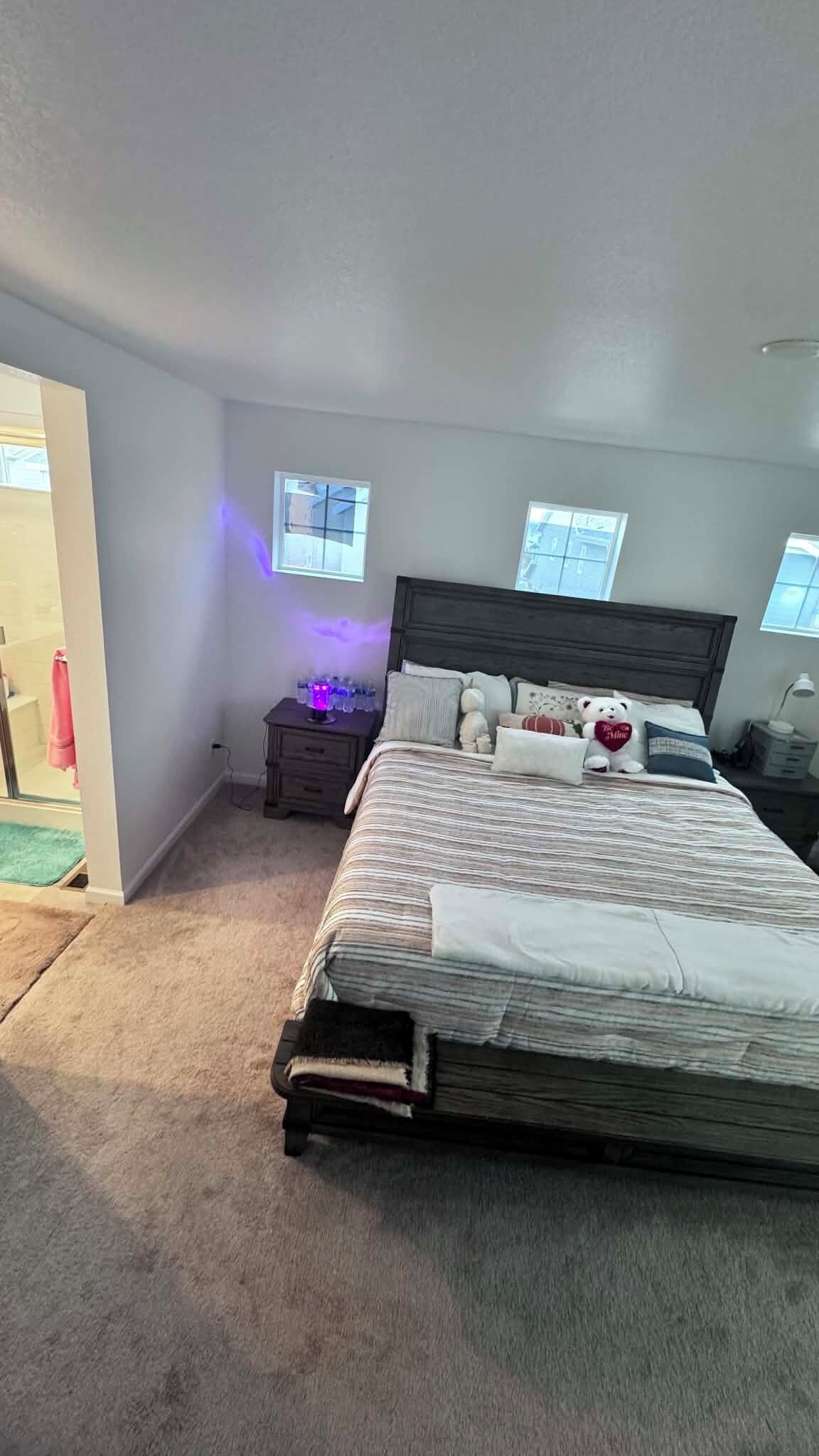 Une chambre à coucher avec un lit, des tables de chevet, une commode, une fenêtre et une porte.