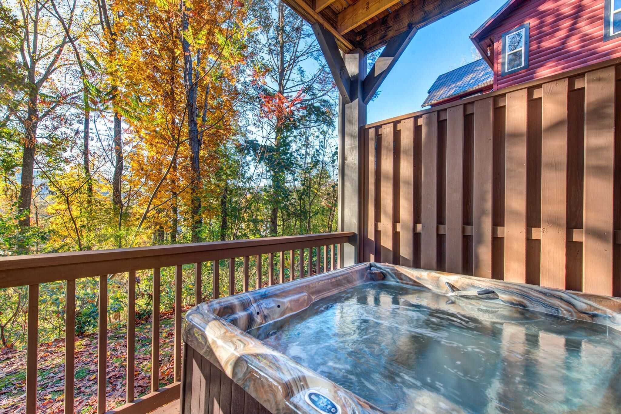 A hot tub on a wooden deck with a view of autumn trees.