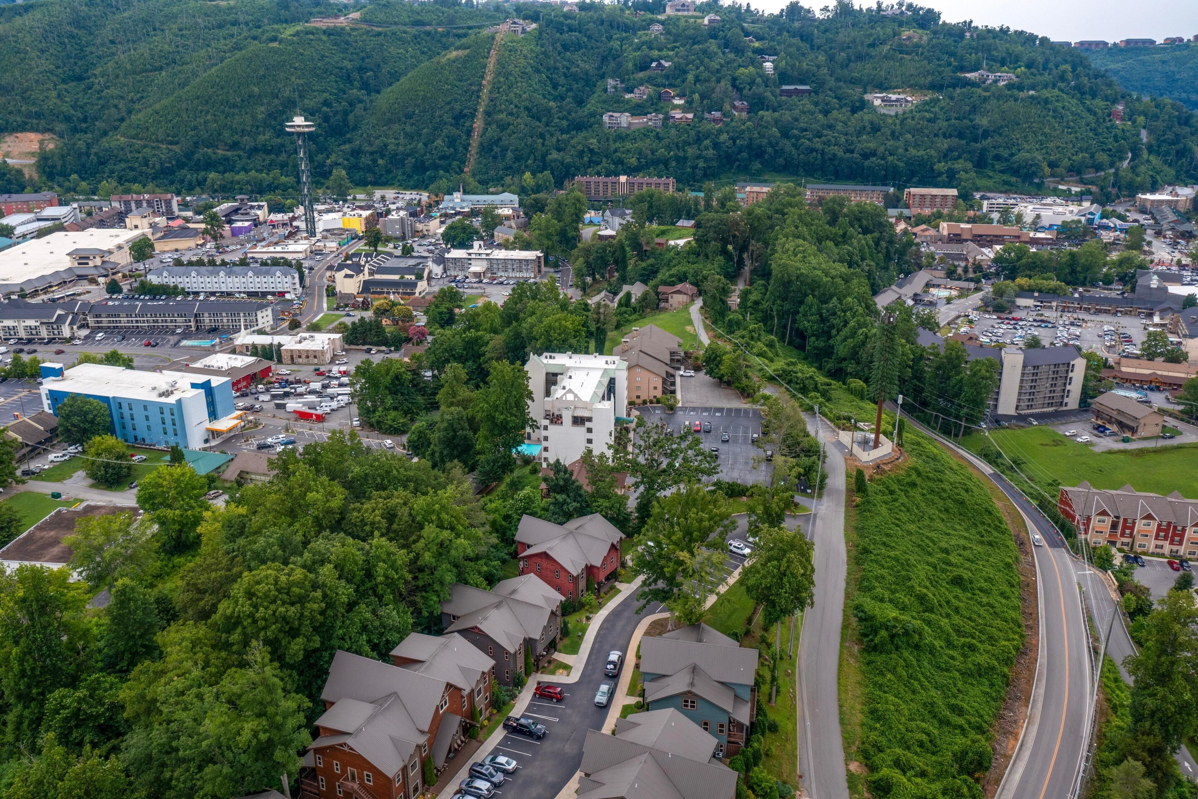 An aerial view of a town with a prominent church, a large blue building, and a winding road.
