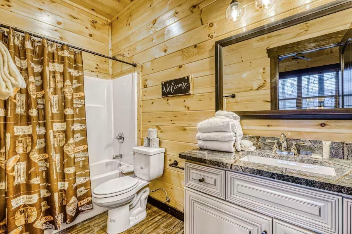 A wooden cabin bathroom with a shower, toilet, sink, and vanity.
