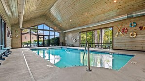 An indoor swimming pool with wooden ceiling and walls, clear windows, and lifebuoys on the wall.