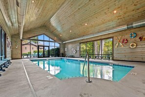 Une piscine intérieure avec un plafond et des murs en bois, de grandes fenêtres et des bouées de sauvetage accrochées au mur.