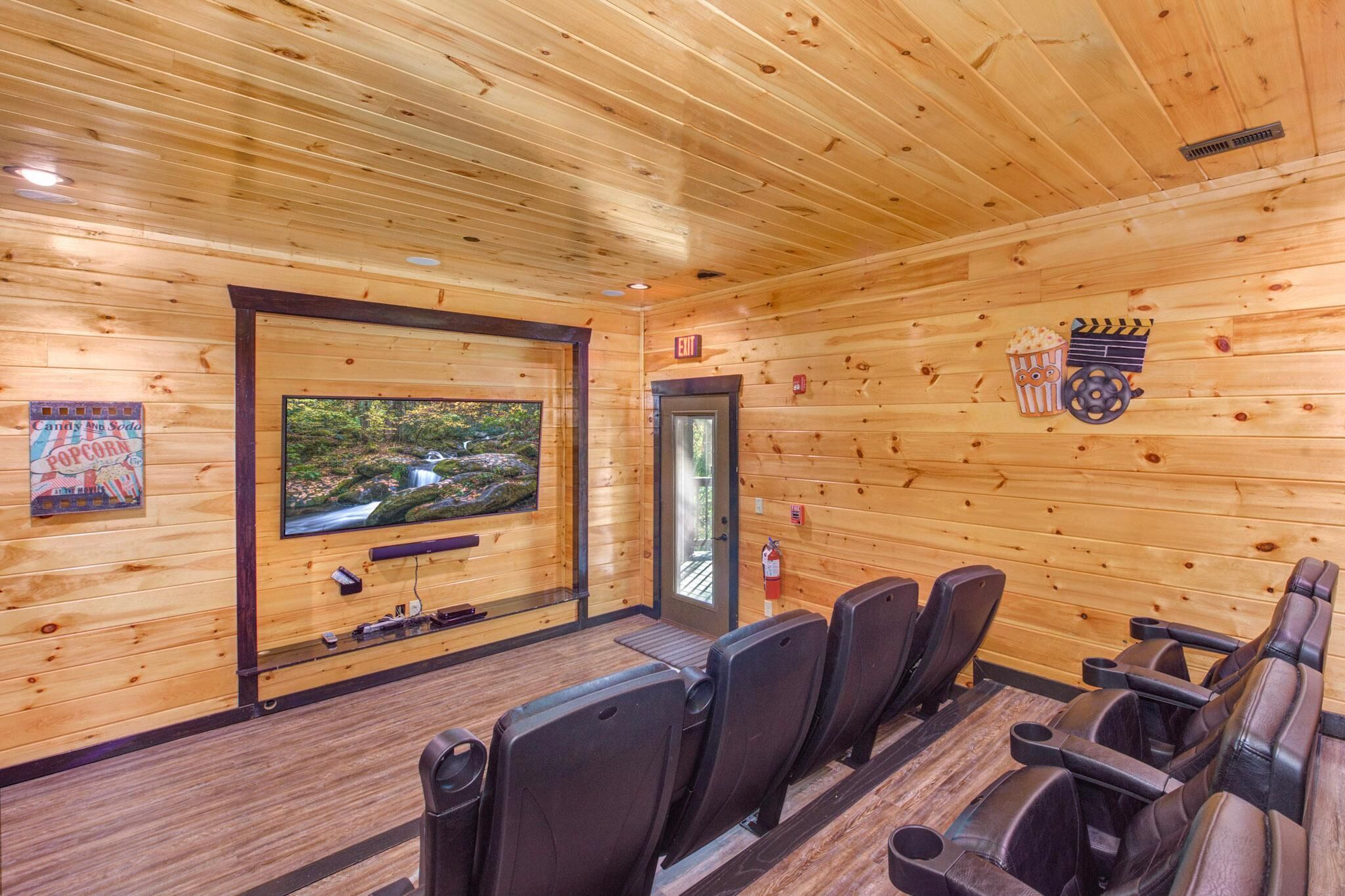 A wooden interior with a large screen, seating, and a poster.