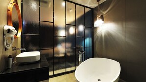 Un baño moderno con una bañera independiente, un tocador con espejo y una lámpara de pared.